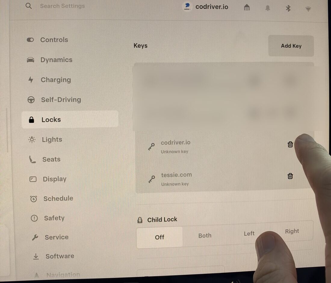 The Locks screen of a Tesla: the key list shows codriver.io with a bin icon, and a finger about to tap it
